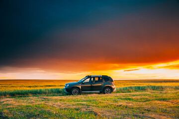 Fototapeta na wymiar AWD 4WD SUV green car in summer meadow landscape in summer field countryside landscape. Sunset sky background.