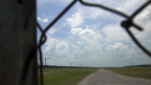Plane Landing On Runway Seen Through Chain Link Fence