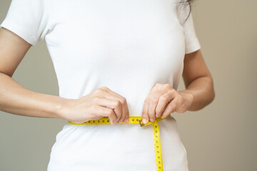 Close-up woman measuring her shape after weight loss session.