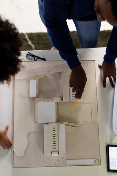 Overhead View Of Diverse Male And Female Architects Standing At Desk Discussing Building Model