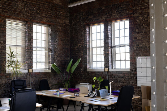 Modern casual office interior with exposed brick walls, desks and chairs