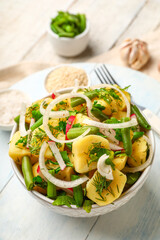 Bowl of tasty Potato Salad with vegetables on light wooden background