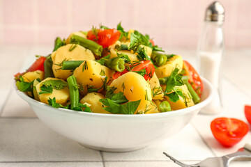Bowl of tasty Potato Salad with vegetables on table, closeup