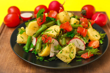 Plate of tasty Potato Salad with vegetables on yellow background, closeup