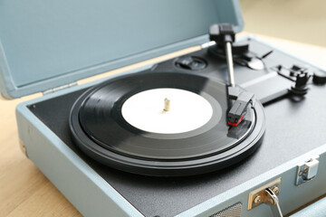 Record player with vinyl disk on table in room, closeup