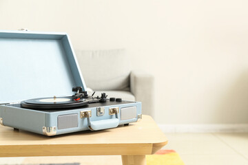 Record player with vinyl disk on table in room