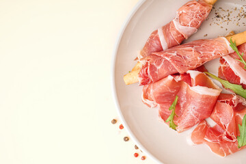 Plate with slices of tasty jamon on yellow background, closeup