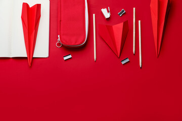 Composition with stationery supplies and paper planes on red background