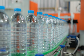 Water factory - Water bottling line for processing and bottling pure mineral water into blue bottles. Selective focus.