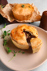 Plate with tasty meat pot pie on light background