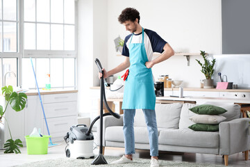 Young man hoovering carpet at home
