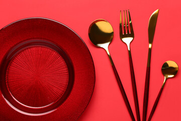 Table setting with clean plate and cutlery on red background
