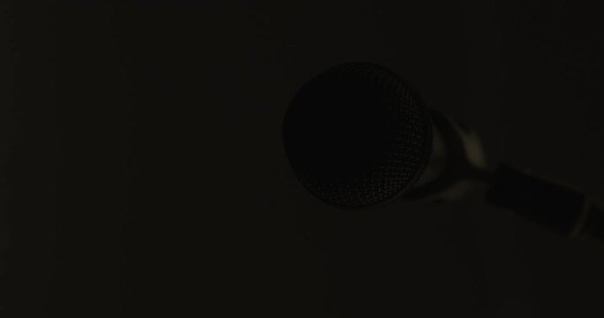 Microphone emerges, illuminates, and returns to darkness elegantly