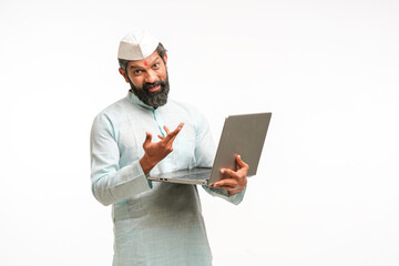 Indian man in traditional wear and using laptop on white background.