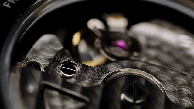 Mechanical watches with gears and cogs. Watch or clock mechanism. Mechanical skeleton watch. Clockwork details and parts.Clock gears running with dramatic flickering light.Open balance extreme closeup