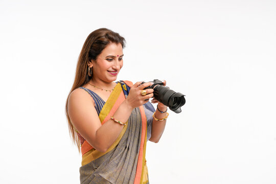 Indian woman in traditional sari and using camera on white background.