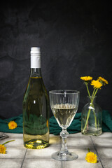 Bottle and glass of dandelion wine on grey tile table