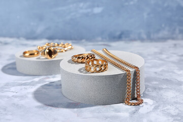 Decorative podium with beautiful jewelry on blue background