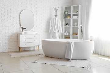 Interior of light bathroom with sink, bathtub and shelving unit
