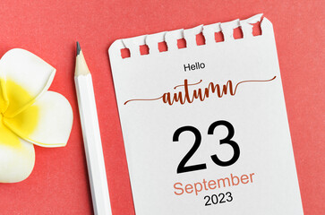 The Hello autumn on 23rd September 2023 calendar and pen with flower on red background.