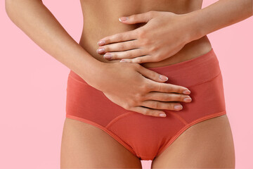 Young woman in menstrual panties on pink background, closeup