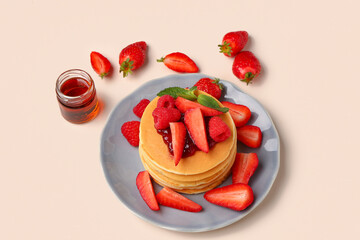 Plate with sweet pancakes, berries and jam on beige background