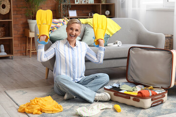 Mature woman with flippers packing suitcase at home © Pixel-Shot