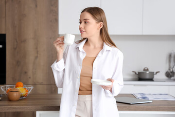 Happy young woman enjoying cup of coffee in modern kitchen