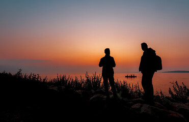 By the sea , silhouette men at sunset