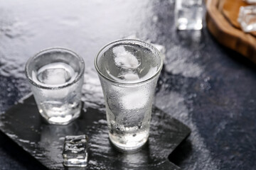 Board with shots of vodka on dark table