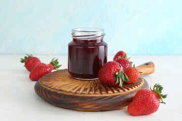 Jar of sweet strawberry jam and fresh berries on table