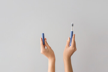 Female hands with insulin syringe on grey background