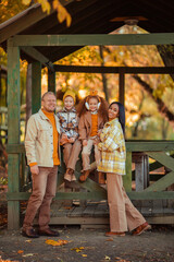 multiethnic family on a walk in the autumn park in a wooden gazebo