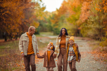 happy multiethnic family in autumn on a walk in the park in warm clothes