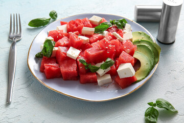 Plate of tasty watermelon salad on light blue background