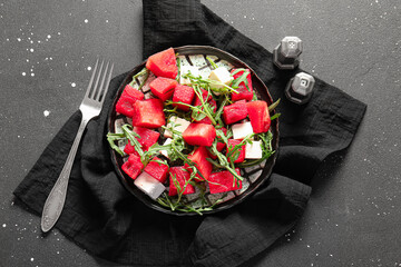Plate of tasty watermelon salad on black background