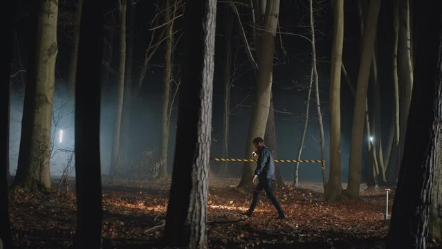 Couple of detectives working on crime scene in night woods, using flashlights and drone, finding something and running into it. Investigators solving mystery case in spooky atmosphere