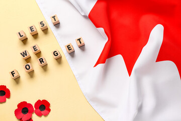 Poppy flowers with flag of Canada and text LEST WE FORGET on yellow background. Remembrance Day