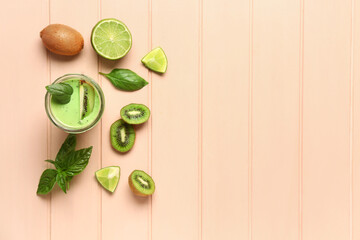 Glass of fresh kiwi smoothie with lime and basil on pink wooden background