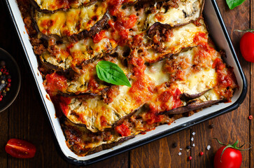 Eggplant Casserole, Roasted Eggplant Dish with Minced Meat, Tomato Sauce and Mozzarella over Rustic Background - obrazy, fototapety, plakaty