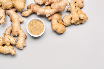 Fresh ginger roots and bowl with dried powder on grey background