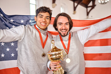 Trophy, sports and portrait of men with American flag, winning at competition and happy games. Smile, performance award and gold medal winner team on podium for celebration of success at challenge.