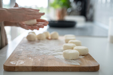 Roll ball of dough between palms in flour for cookies. Cook food. Hands in flour shaping pie pastry. Process of making dessert for breakfast in home kitchen. Raw home made bread, buns.