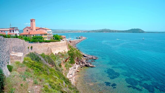Talamone rocky beach and medieval fortress Rocca Aldobrandesca and walls. The village lies on a rocky promontory, in Maremma nature reserve, mount Argentario, Tuscany, Italy