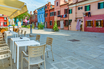 A small Piazzetta with outdoor restaurants cafes and colorful building in the island of Burano, Venice.