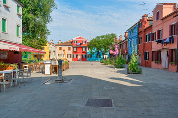 A small Piazzetta with outdoor restaurants cafes and colorful building in the island of Burano,...