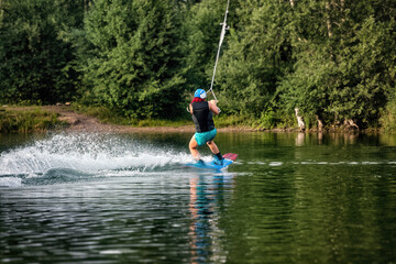 Wakeboarding on the sea on summer day in life jacket. Soft focus. Action blur.