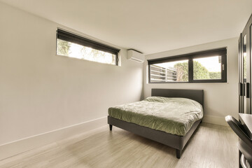 a bedroom with white walls and wood flooring in the middle of the room there is a small bed on the other side