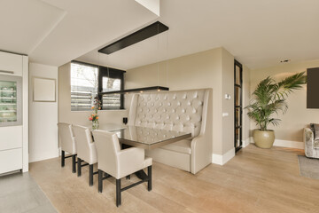 a dining room with white chairs and a large plant in the center of the room is an open kitchen area