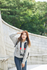young woman who is taking pictures while traveling in Korea with a camera backpack